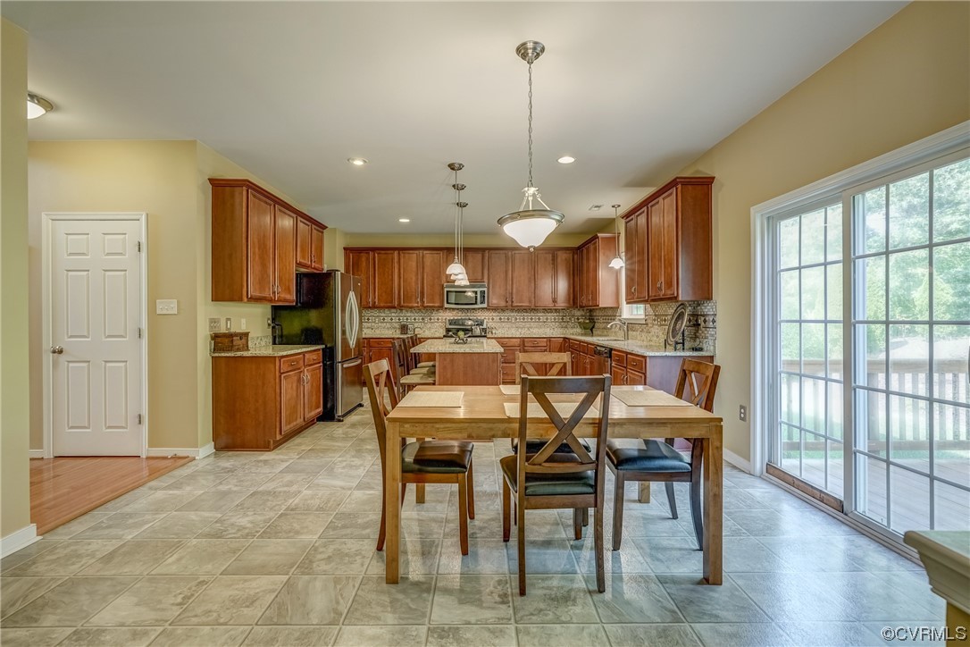 2407 Cascade Meadows Drive Midlothian, VA 23112 - Photo 20 of 48 a kitchen with stainless steel appliances kitchen island granite countertop a refrigerator a stove a sink a dining table and chairs with wooden floor