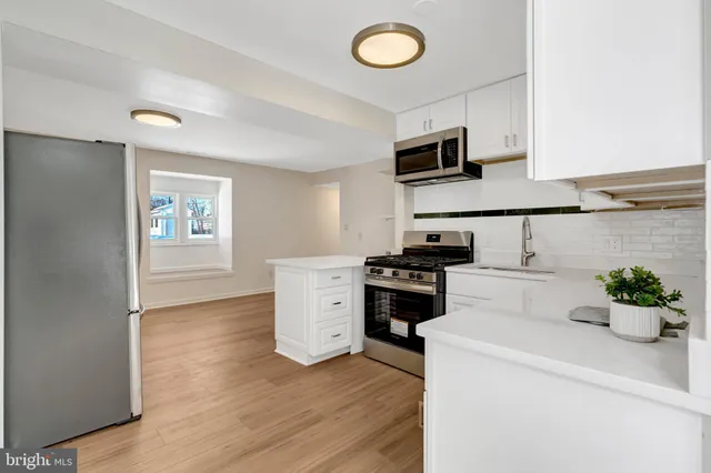 a kitchen with cabinets stainless steel appliances and wooden floor