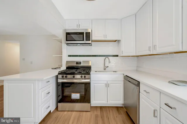 a kitchen with white cabinets and appliances