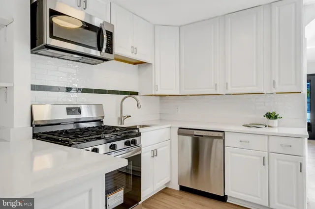 a kitchen with a refrigerator and white cabinets