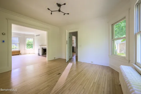 a view of an empty room with wooden floor and a window