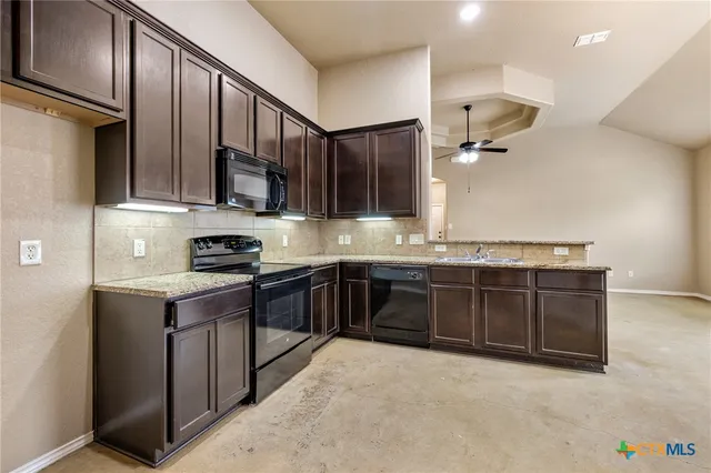 a kitchen with stainless steel appliances granite countertop a stove a sink and a refrigerator