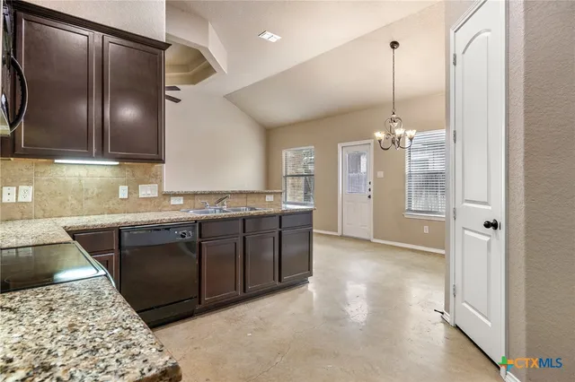a kitchen with granite countertop a refrigerator and a sink