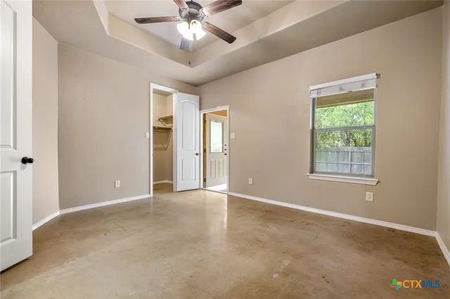 an empty room with windows and fan