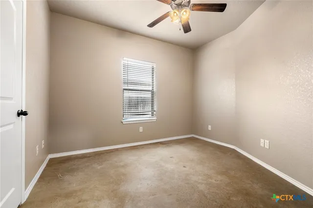 an empty room with windows and fan