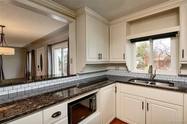 a kitchen with granite countertop a sink window and cabinets