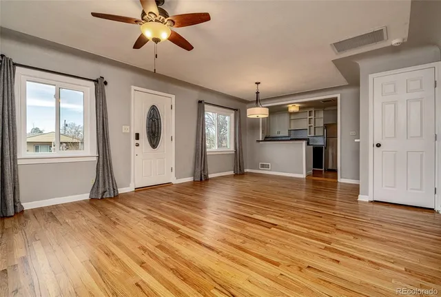 a view of empty room with wooden floor and fan