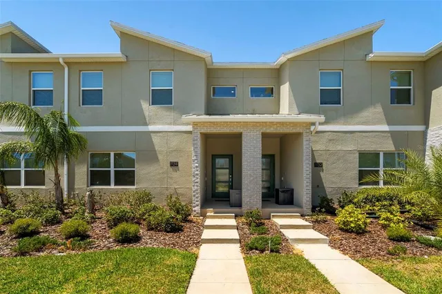 a view of a white house with a yard and plants