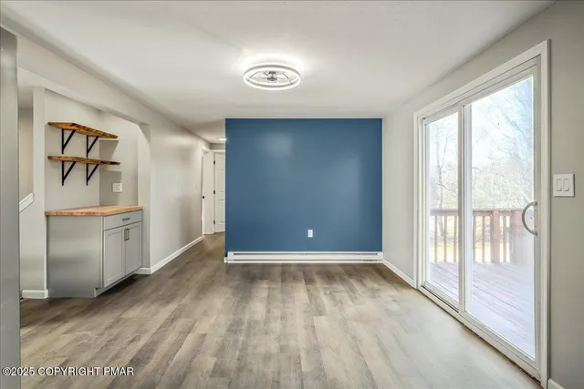 a view of empty room with wooden floor and white walls