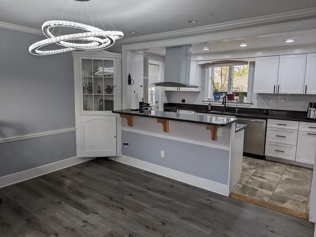 a kitchen with stainless steel appliances granite countertop a white cabinets a sink dishwasher and a stove with wooden floor