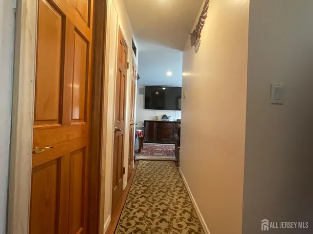 a view of a hallway with wooden floor and a bathroom