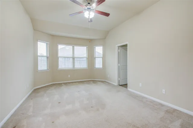 an empty room with a window and a fan