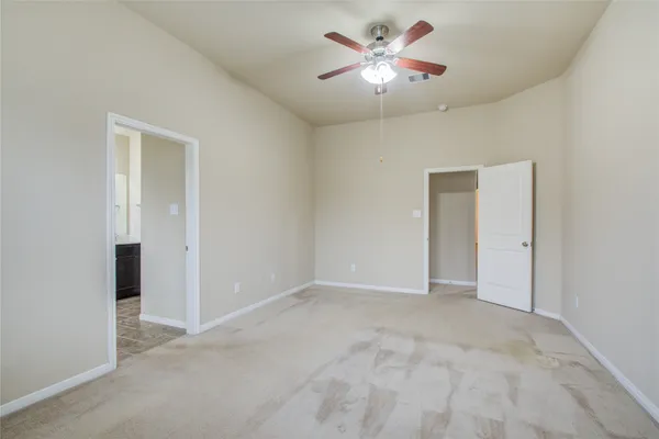 an empty room with chandelier fan and closet