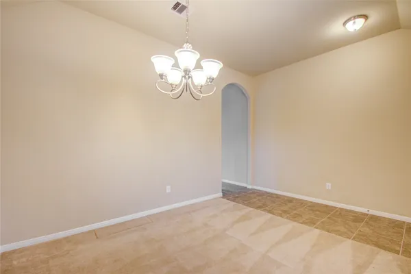 a view of an empty room with a chandelier fan