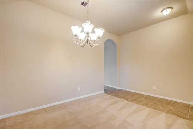 a view of an empty room with a chandelier fan
