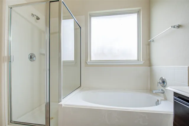 a white bath tub sitting next to a white sink and a window