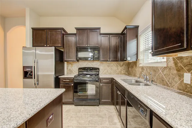 a kitchen with stainless steel appliances granite countertop a sink stove microwave and refrigerator
