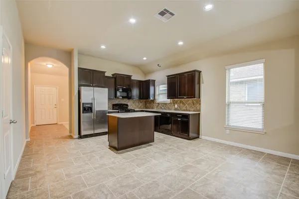 a large kitchen with stainless steel appliances kitchen island granite countertop a refrigerator and a stove top oven