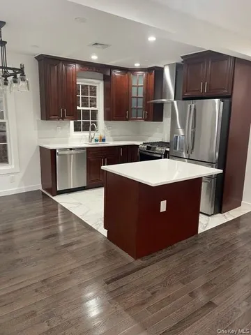 a large kitchen with kitchen island granite countertop wooden cabinets a refrigerator and a sink