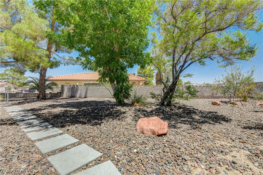 7631 Bermuda Road Las Vegas, NV 89123 - Photo 48 of 64 A desert-friendly yard showcases mature trees and a neatly arranged stepping stone path.