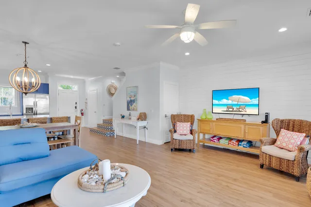 a living room with furniture a dining table wooden floor and a kitchen view