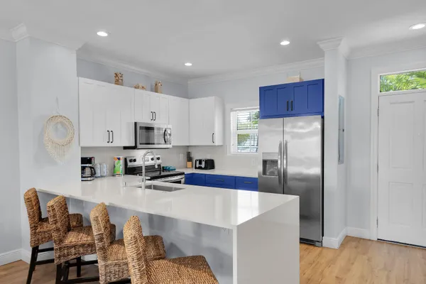 a kitchen with stainless steel appliances a sink a stove a refrigerator cabinets and a dining table