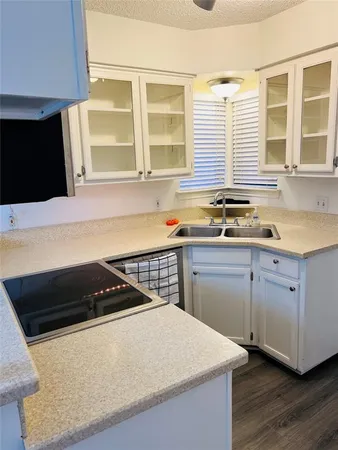 a kitchen with granite countertop a sink a stove and cabinets