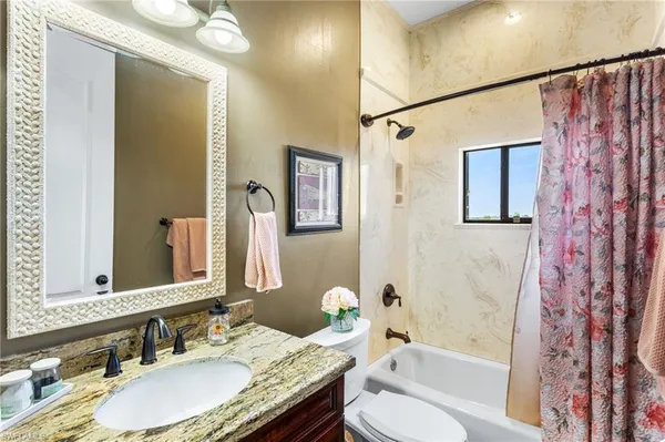 a bathroom with a granite countertop tub sink and mirror