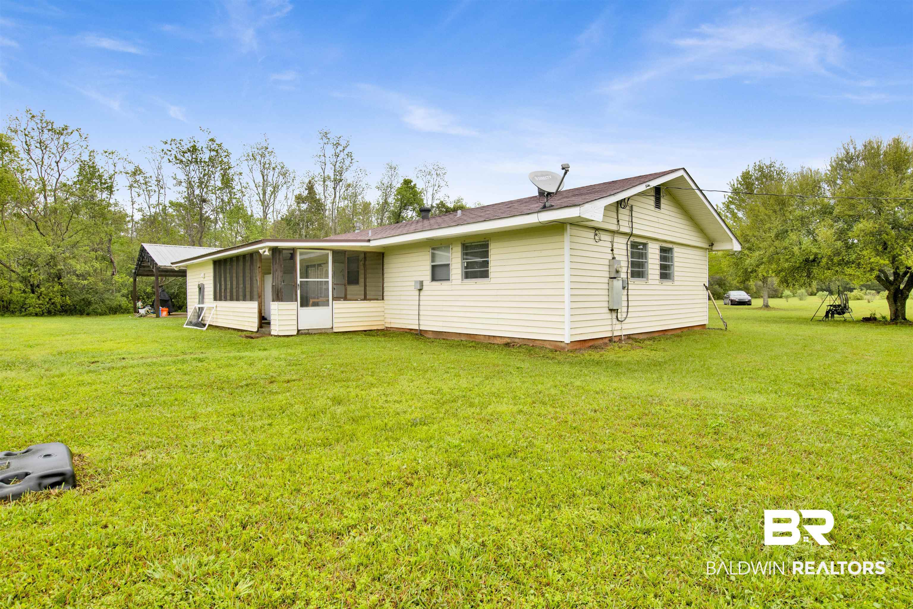 10244 Magnolia Road Irvington, AL 36544 - Photo 31 of 37 Rear view of house featuring a sunroom and a lawn
