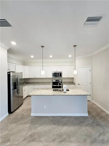 a large white kitchen with a large counter top stainless steel appliances and cabinets