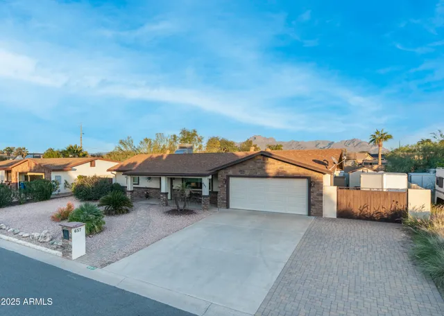 a view of a white house with a yard and table and chairs under an umbrella
