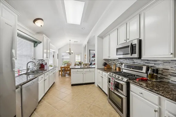 a large kitchen with stainless steel appliances granite countertop a stove and a sink