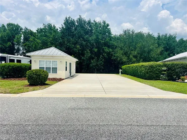 a view of a house with backyard and bushes
