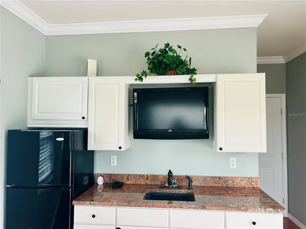 a kitchen with stainless steel appliances a sink a stove a refrigerator a washer dryer and white cabinets