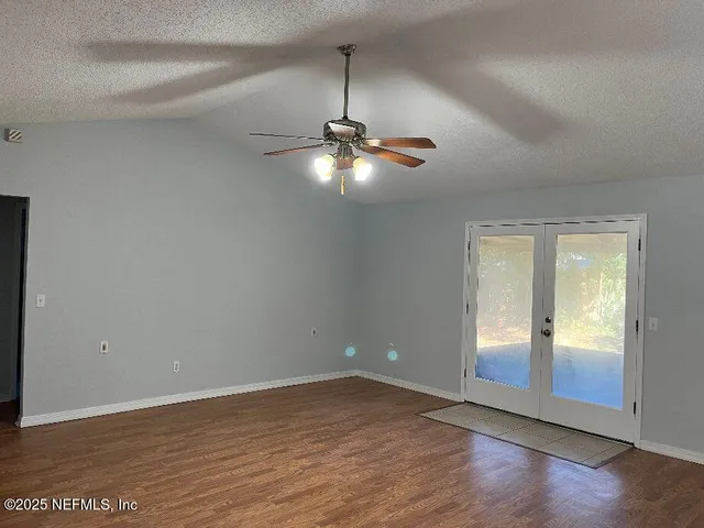 an empty room with wooden floor and windows