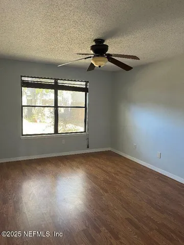 an empty room with wooden floor chandelier and windows