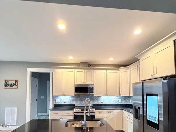 a kitchen with granite countertop a stove a sink and a refrigerator