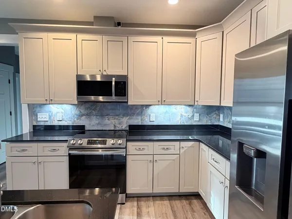 a kitchen with granite countertop white cabinets and black appliances