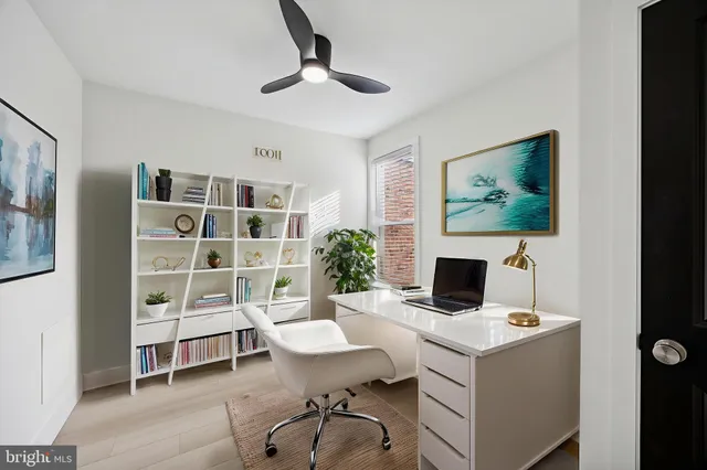 a work room with furniture a bookshelf and a potted plant