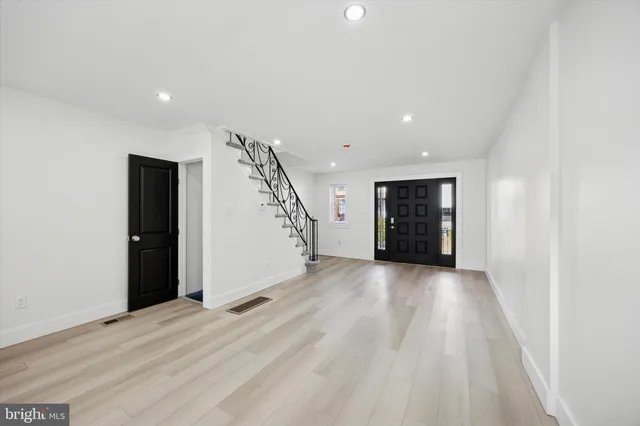 a view of an empty room with wooden floor and stairs
