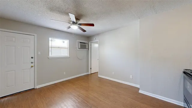 an empty room with wooden floor ceiling fan and windows