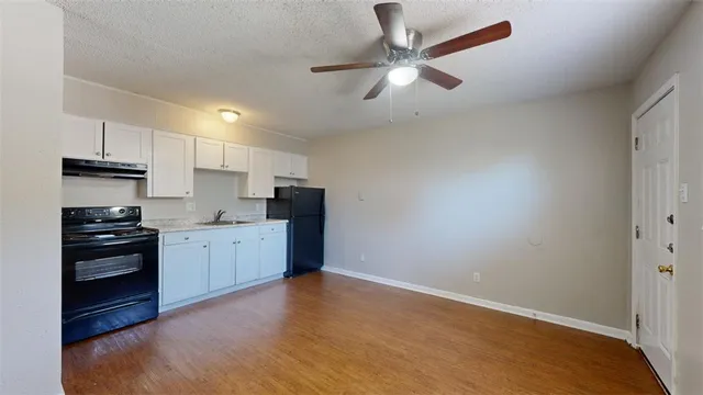 a kitchen with stainless steel appliances granite countertop a refrigerator a stove a sink and white cabinets with wooden floor