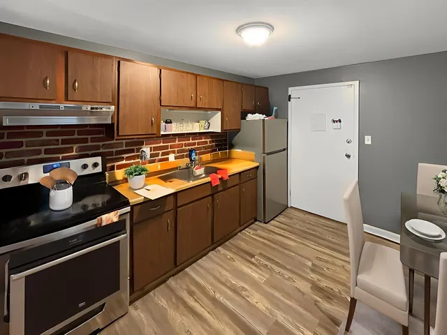 a kitchen with stainless steel appliances a refrigerator a sink and wooden cabinets