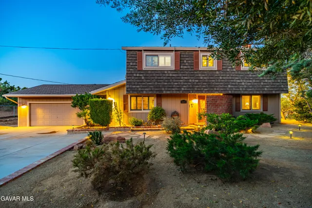 a kitchen with stainless steel appliances granite countertop a refrigerator a stove and a dining table with wooden floors