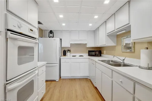 a kitchen with white cabinets sink and stove