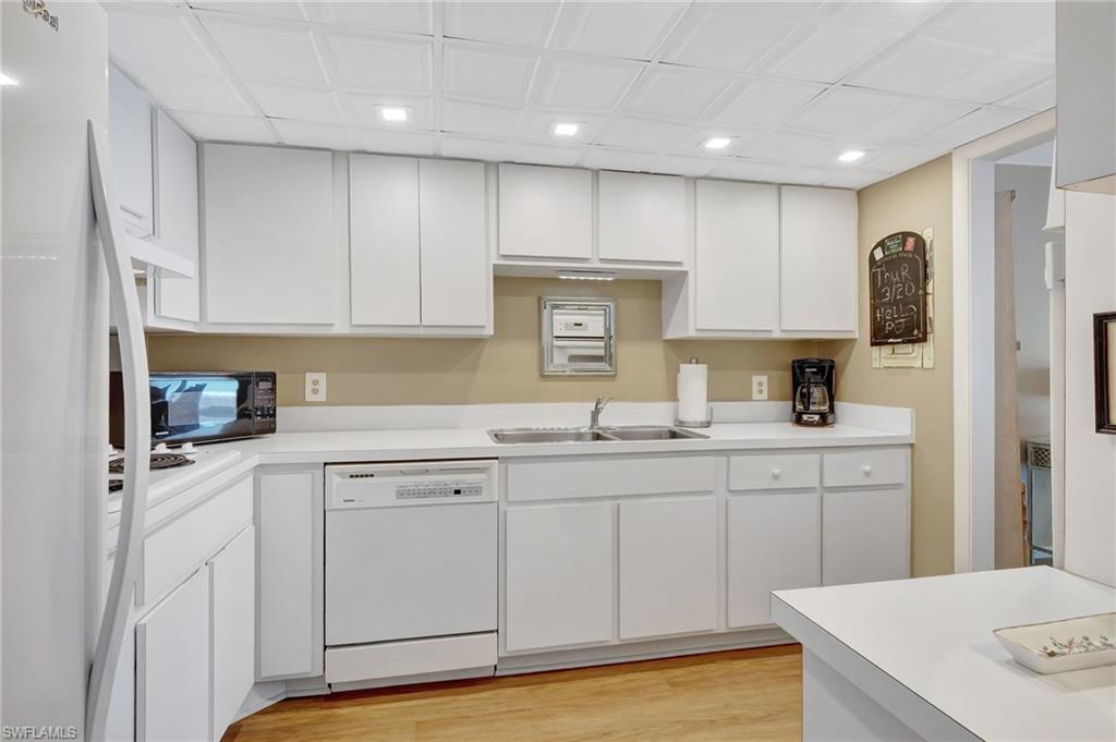 1919 Gulf Shore Boulevard North, Unit 201 Naples, FL 34102 - Photo 12 of 28 a kitchen with white cabinets sink and stove