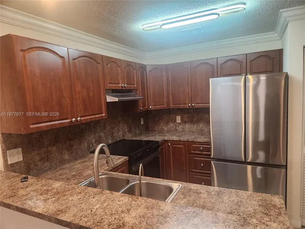 a kitchen with granite countertop a refrigerator and a sink