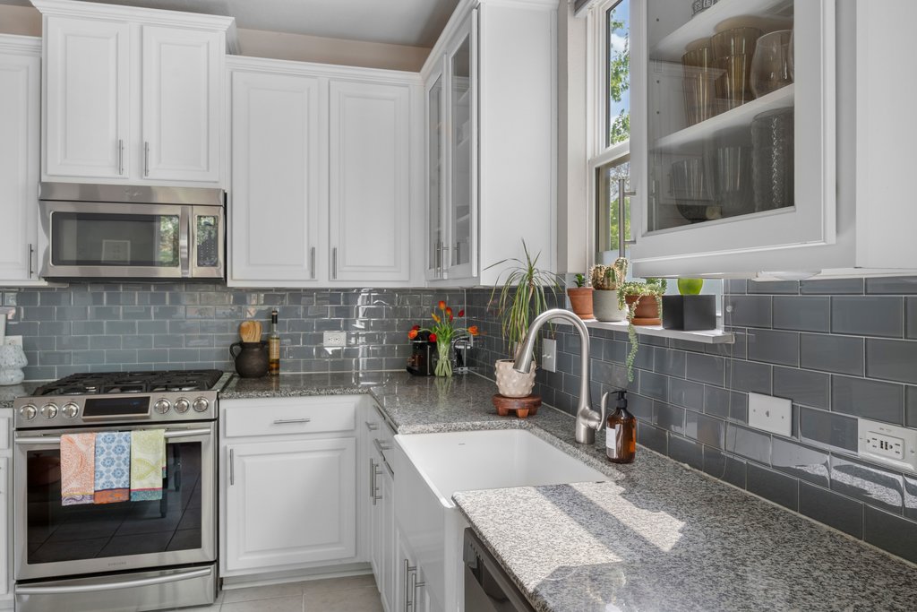 610 Bernstein Street, Unit 14 Austin, TX 78745 - Photo 12 of 39 Kitchen with stainless steel appliances, white cabinets, light stone counters, decorative backsplash, and glass fronted cabinets