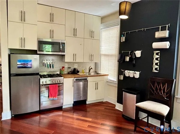 a kitchen with stainless steel appliances granite countertop a refrigerator a stove top oven and a dining table with wooden floor