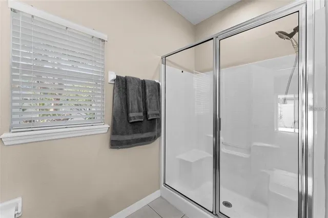 an empty room with chandelier fan and windows